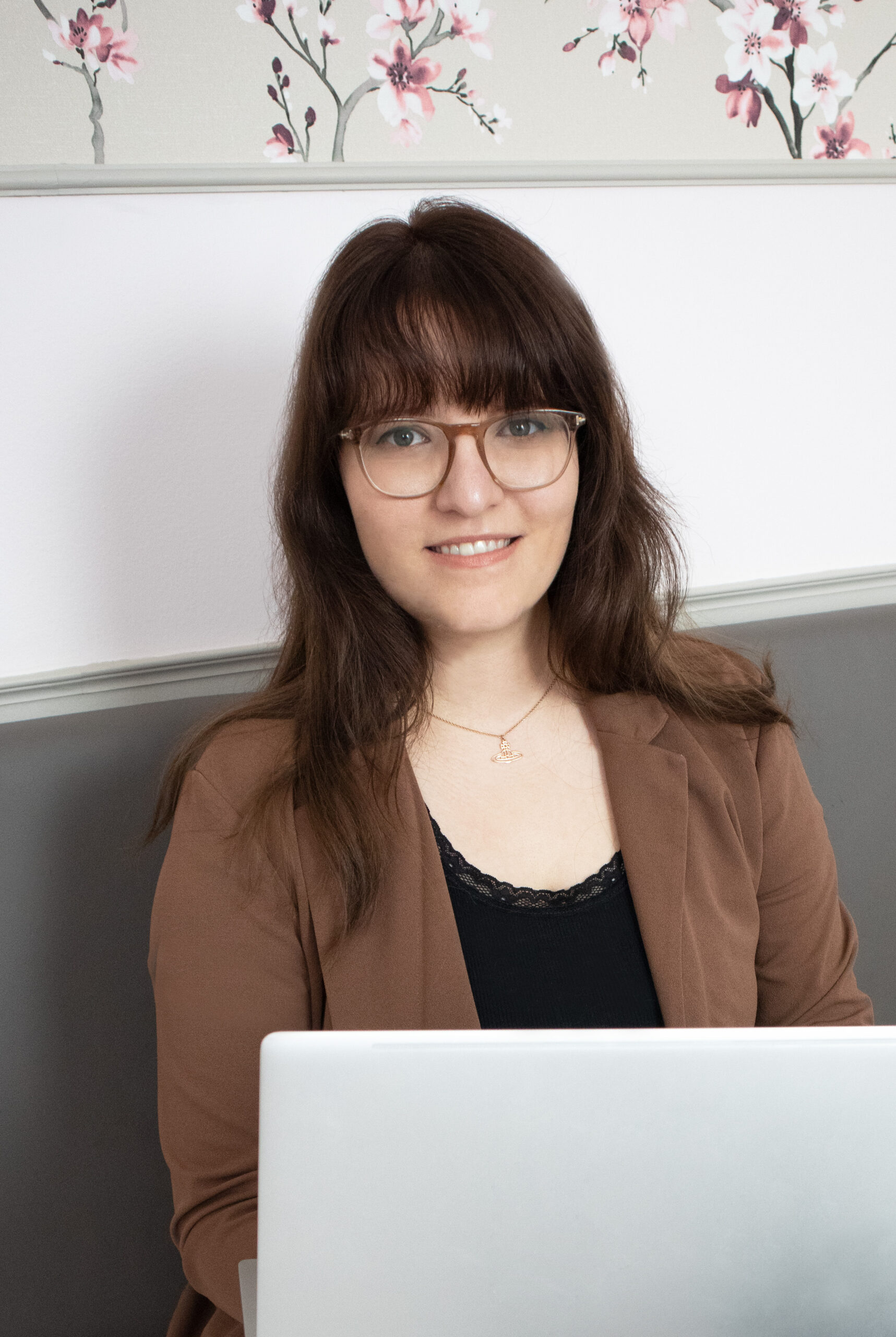 Eine junge Frau - die freie Texterin - schaut lächelnd in die Kamera und hält ein Laptop in der Hand.