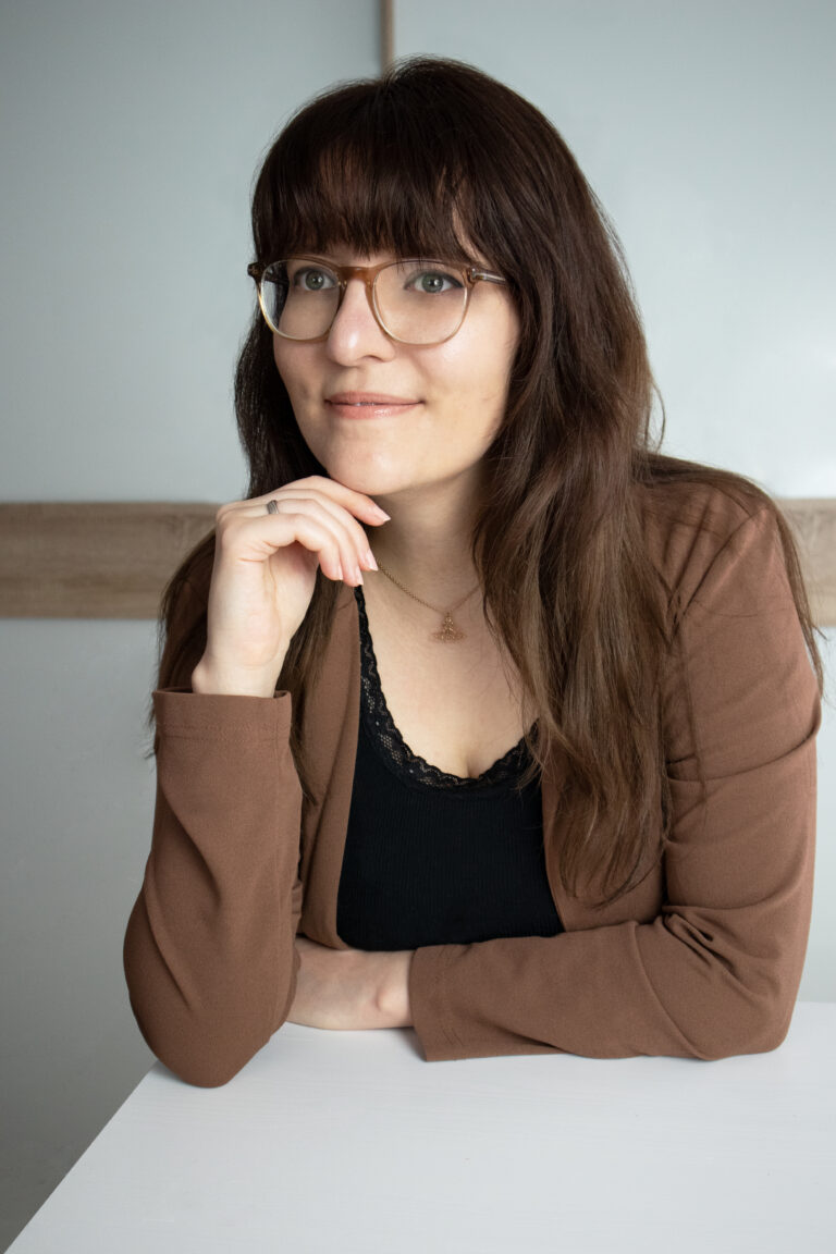 Die freie Texterin, Sarah Kreuzer, stützt ihr Kinn an ihrer Hand ab und schaut zur Seite.