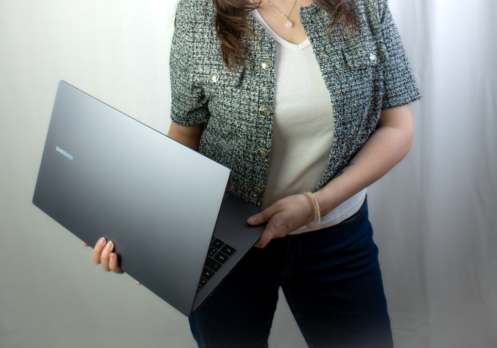 Bildausschnitt vom Hals abwärts von der freien Texterin, Sarah Kreuzer. Sie hält ihr Laptop in der Hand.