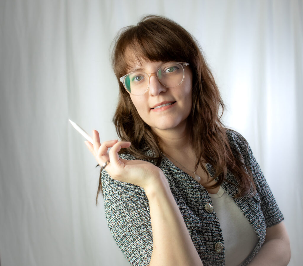 Die freie Texterin, Sarah Kreuzer, lächelt in die Kamera. In ihrer Hand hält sie einen iPen.