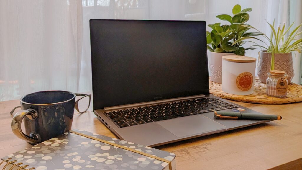 Sinnbild für Storytelling Marketing als thumbnail: Ein Laptop steht auf einem Schreibtisch. Links davon sind eine Kaffeetasse und ein Notizbuch. Auf der rechten Seite stehen einige Pflanzen und eine Kerze.